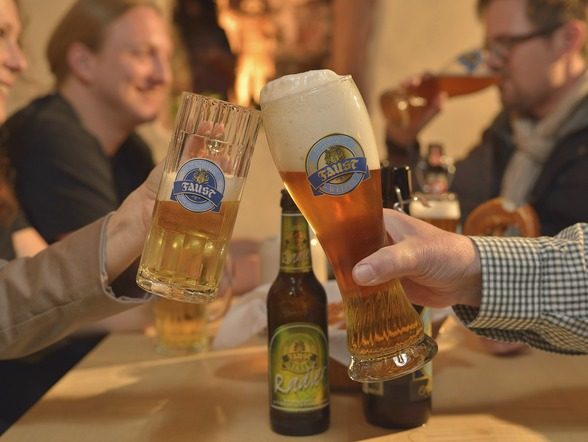 Gäste stoßen bei einer Brauereiführung im Brauhaus Faust mit Bier an.
