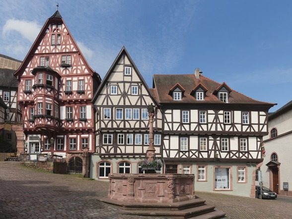 Fachwerkhäuser am Alten Marktplatz in Miltenberg mit steinernem Brunnen.